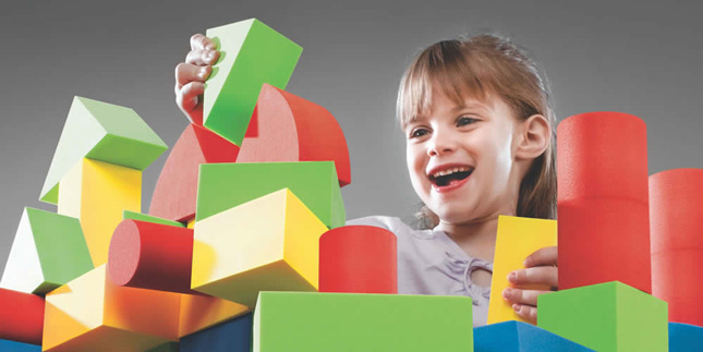 увлеченная девочка строит замок из кубиков